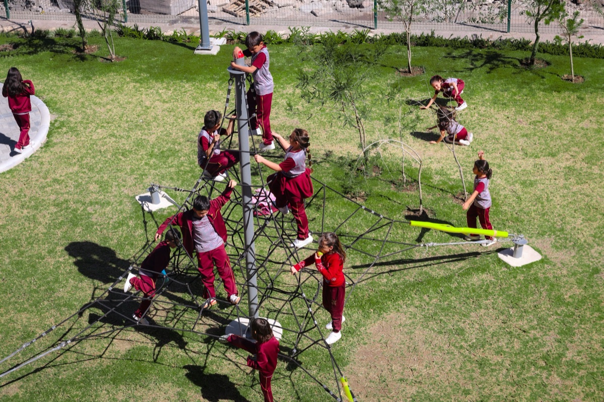 Students on rope pyramid climbing structure during recess at Newland
